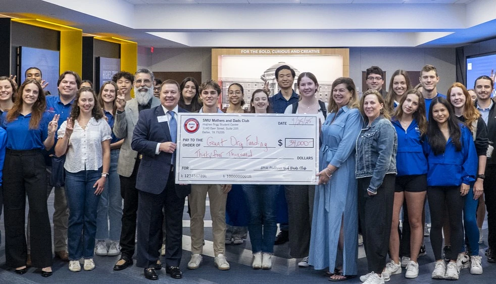 A group of people is gathered in a building holding a large ceremonial check.